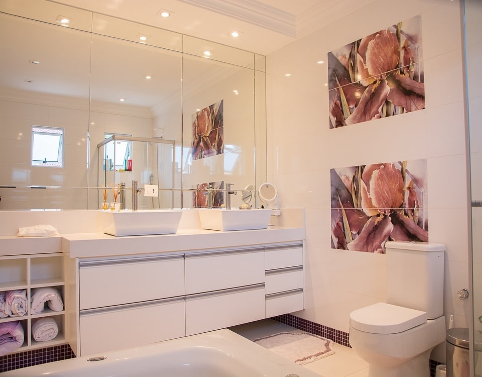 A new bathroom renovated with big mirror on the wall and 2 floral paintings